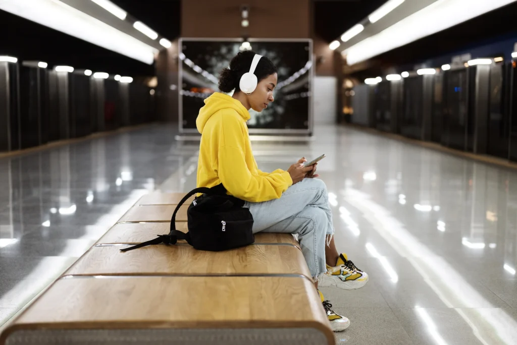 Student sitting at a subway station listening to Spotify premium free trial 3 months